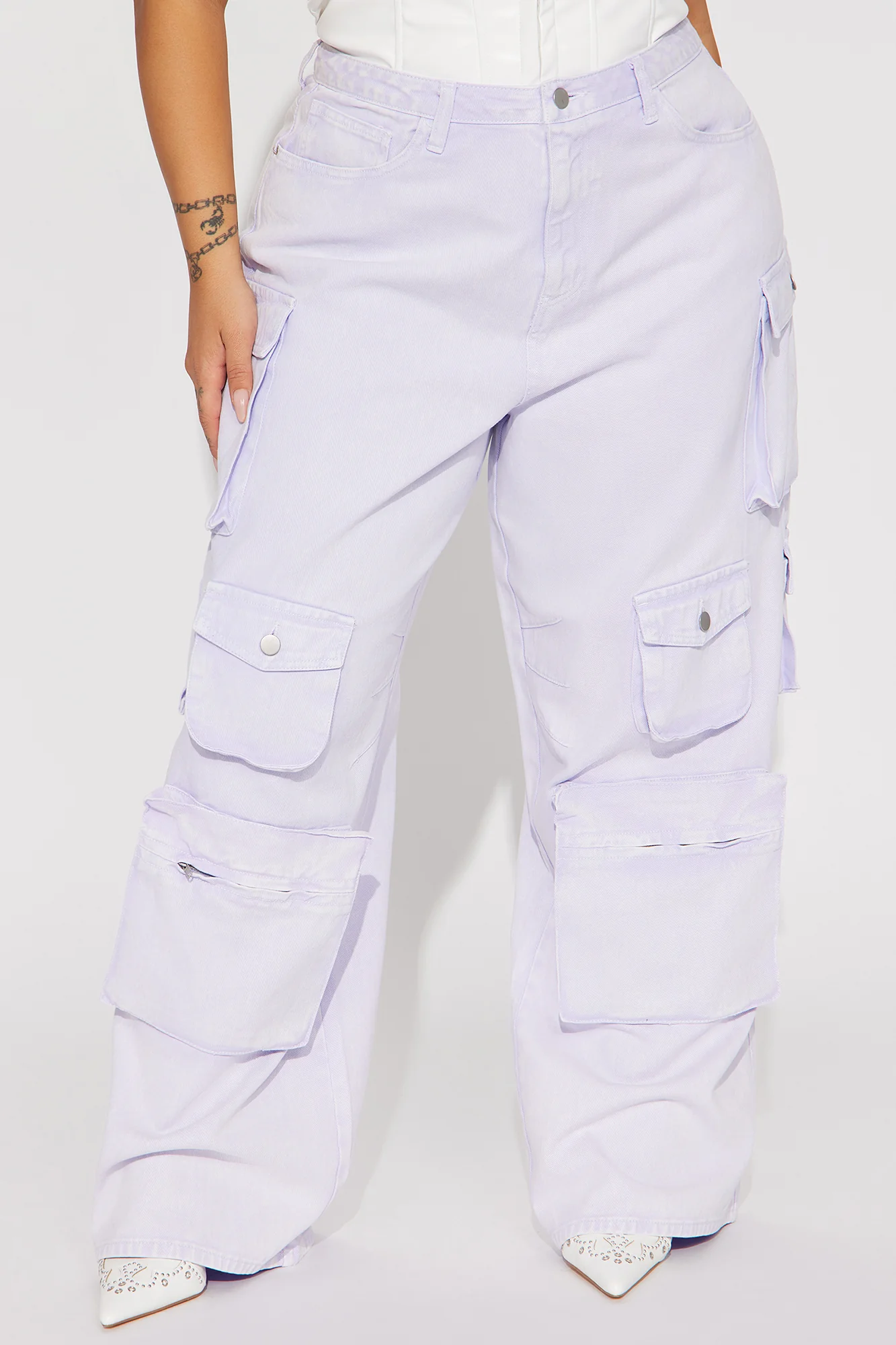 Une femme porte le pantalon cargo lavande nommé Gaëlle, confectionné en gabardine de coton. Ce pantalon large est doté de multiples poches fonctionnelles et d’une teinte pastel douce.
