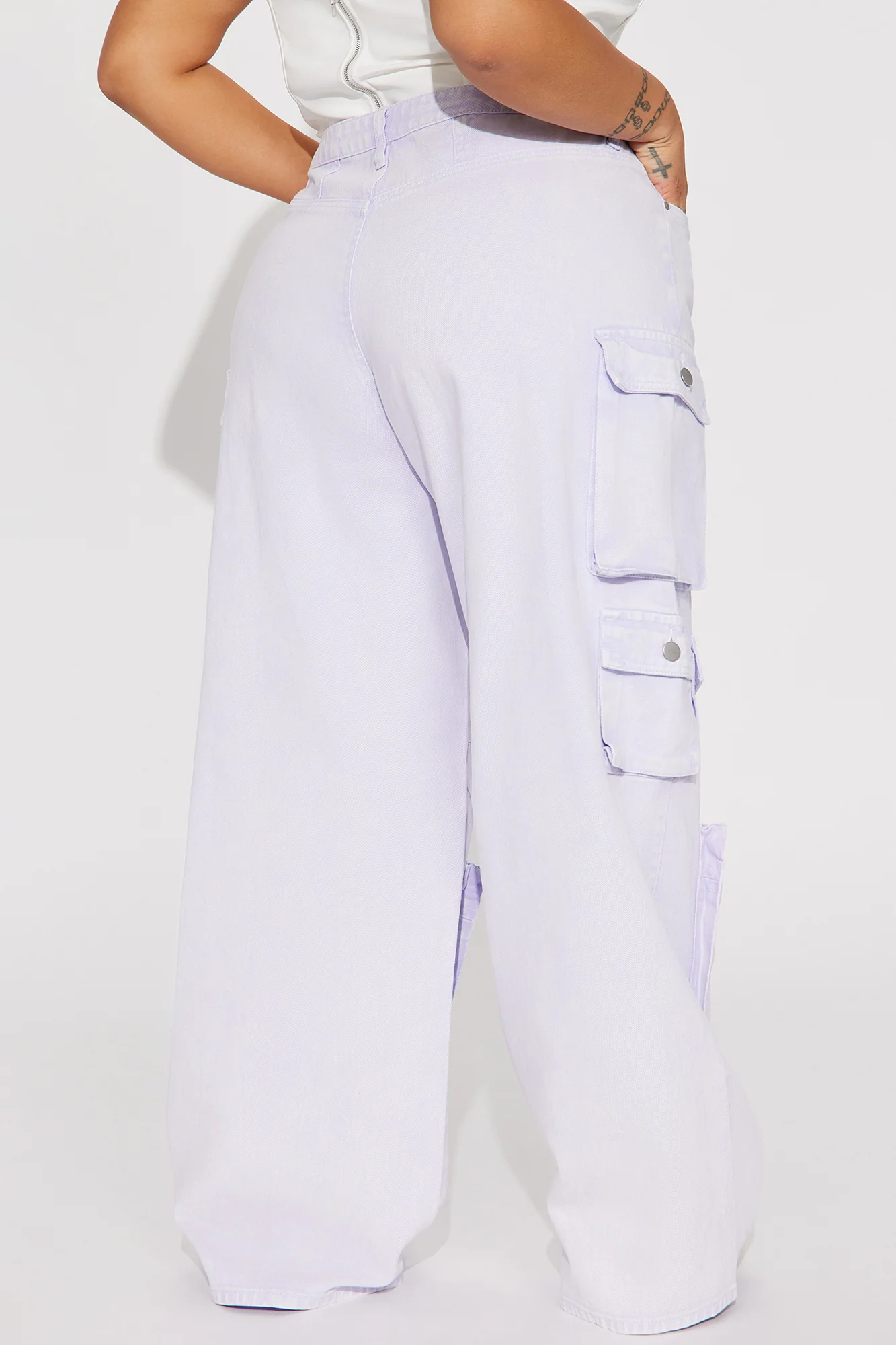 Une femme porte le pantalon cargo lavande nommé Gaëlle, confectionné en gabardine de coton. Ce pantalon large est doté de multiples poches fonctionnelles et d’une teinte pastel douce.