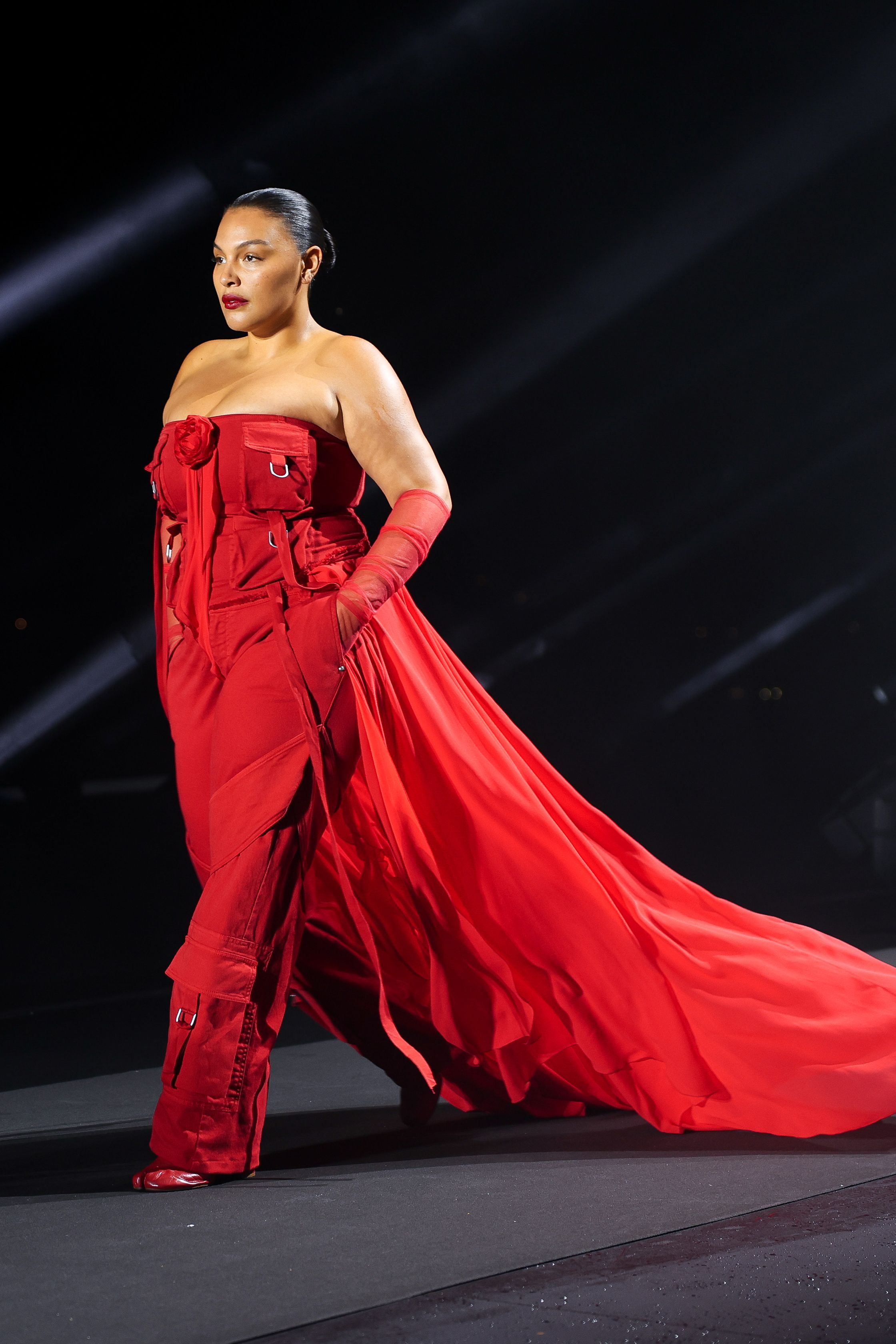 Paloma Elsesser défile à Florence pour «Runway Icons» en combinaison bustier rouge avec traîne, posture forte et élégante.