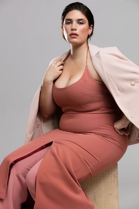 Clémentine Desseaux assise en robe longue rose poudré et blazer clair, pose naturelle, confiante, sur fond neutre.